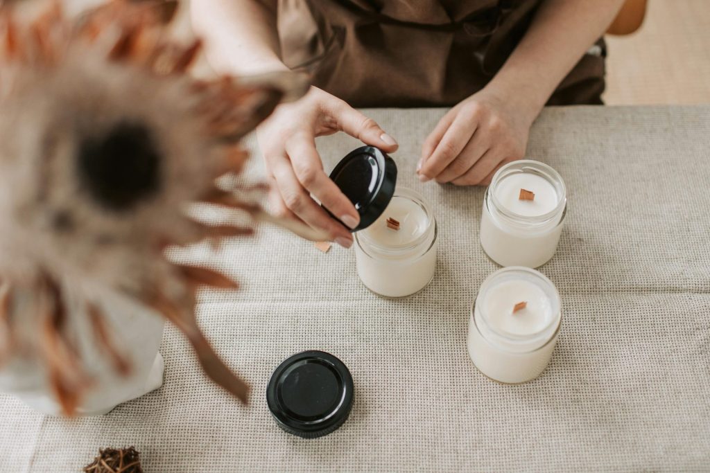 A close-up shot of a person making handmade candles in a cozy indoor workshop setting.